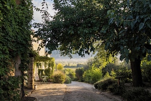 Un chemin de pierres qui traverse un jardin et offre une vue sur un village situé au loin.