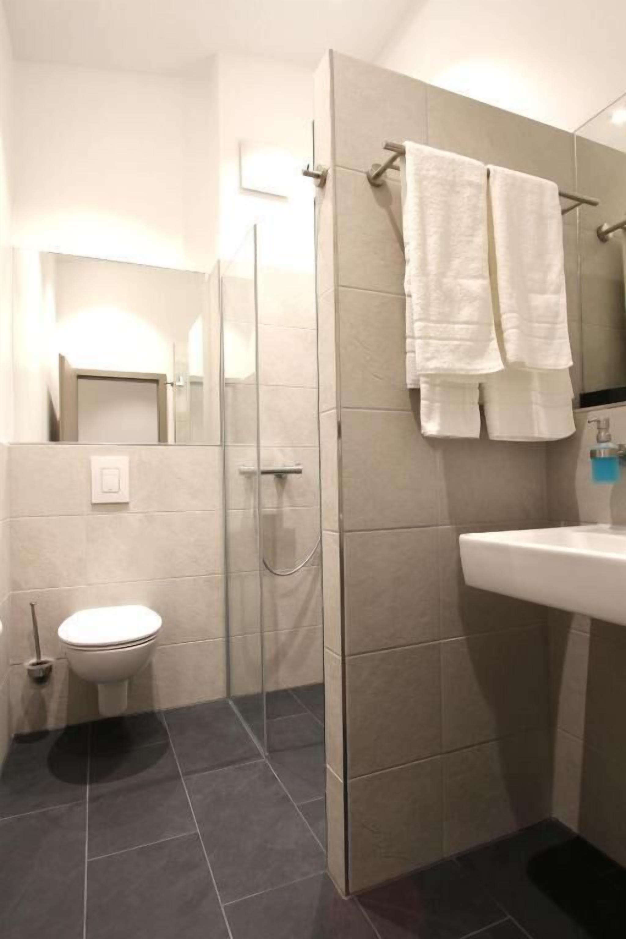 A bathroom with a toilet, a sink, a glass shower enclosure, and a mirror.
