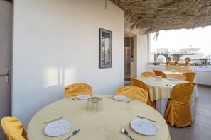 A dining area with round tables, yellow chairs, and a thatched roof. - Treebo Hub (Indore)
