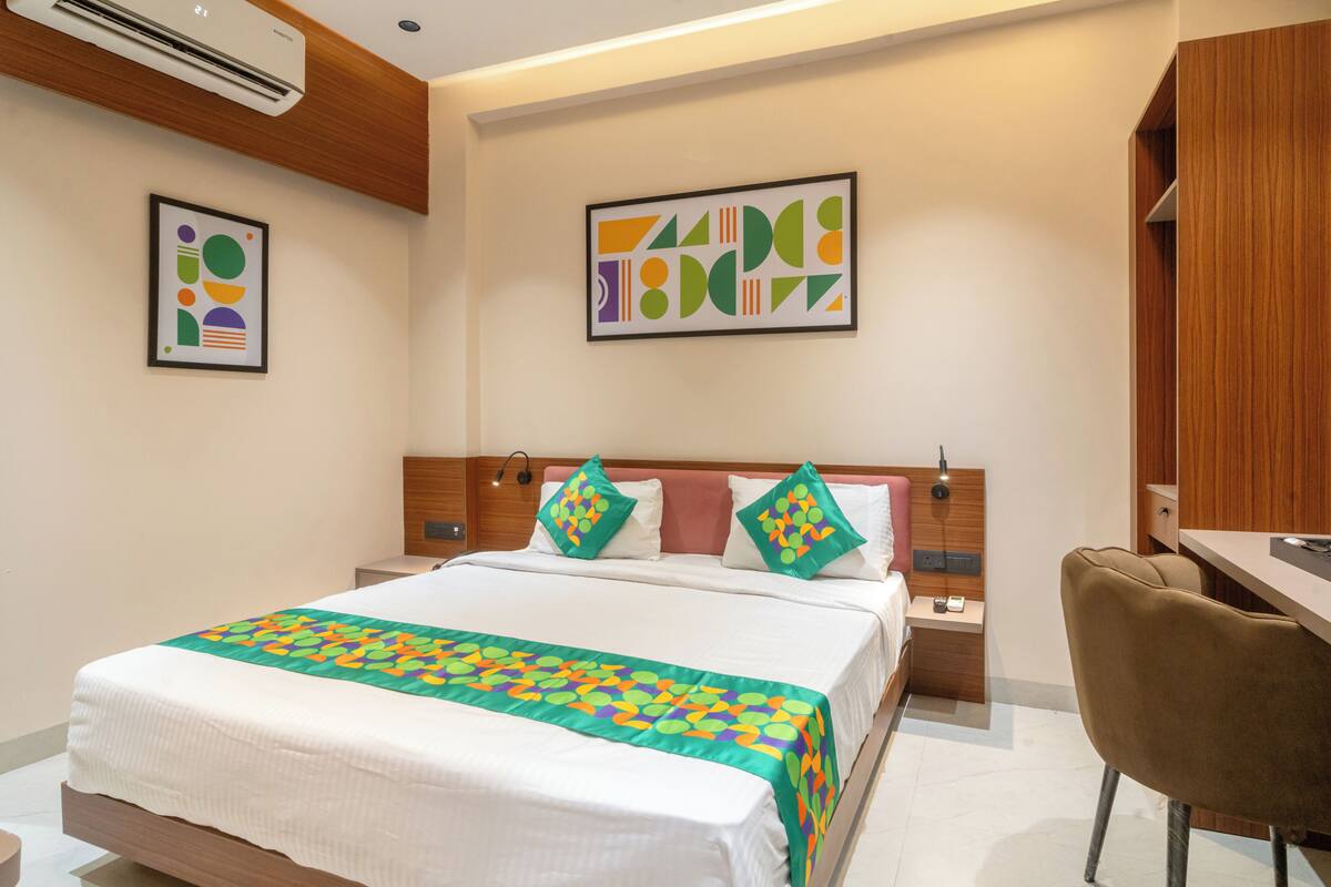 A hotel room with a bed, a desk, and two wall art pieces.
