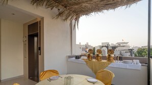 A dining area with a table set for four, a thatched roof, and a city view. - Treebo Hub (Indore)