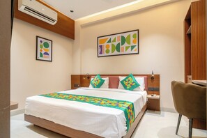 A modern hotel room with a wooden bed frame, a desk, and a chair. - Treebo Hub (Indore)