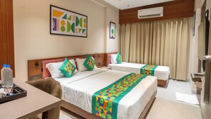 A hotel room with two beds, a desk, a chair, an air conditioning unit, and a ceiling fan. - Treebo Hub (Indore)