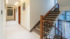 A hallway with a staircase, wooden doors, and a window with a geometric pattern. - Treebo Hub (Indore)