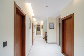A hallway with wooden doors, framed pictures, and recessed lighting. - Treebo Hub (Indore)