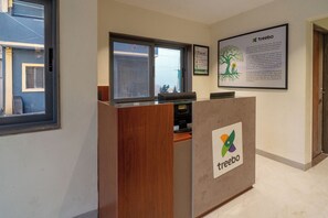 A reception desk with a logo, a window, and a framed informational poster. - Treebo Hub (Indore)
