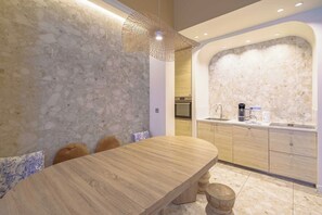 Eine moderne Küche mit einer Rückwand aus Stein, Holzschränken und einem eingebauten Backofen.