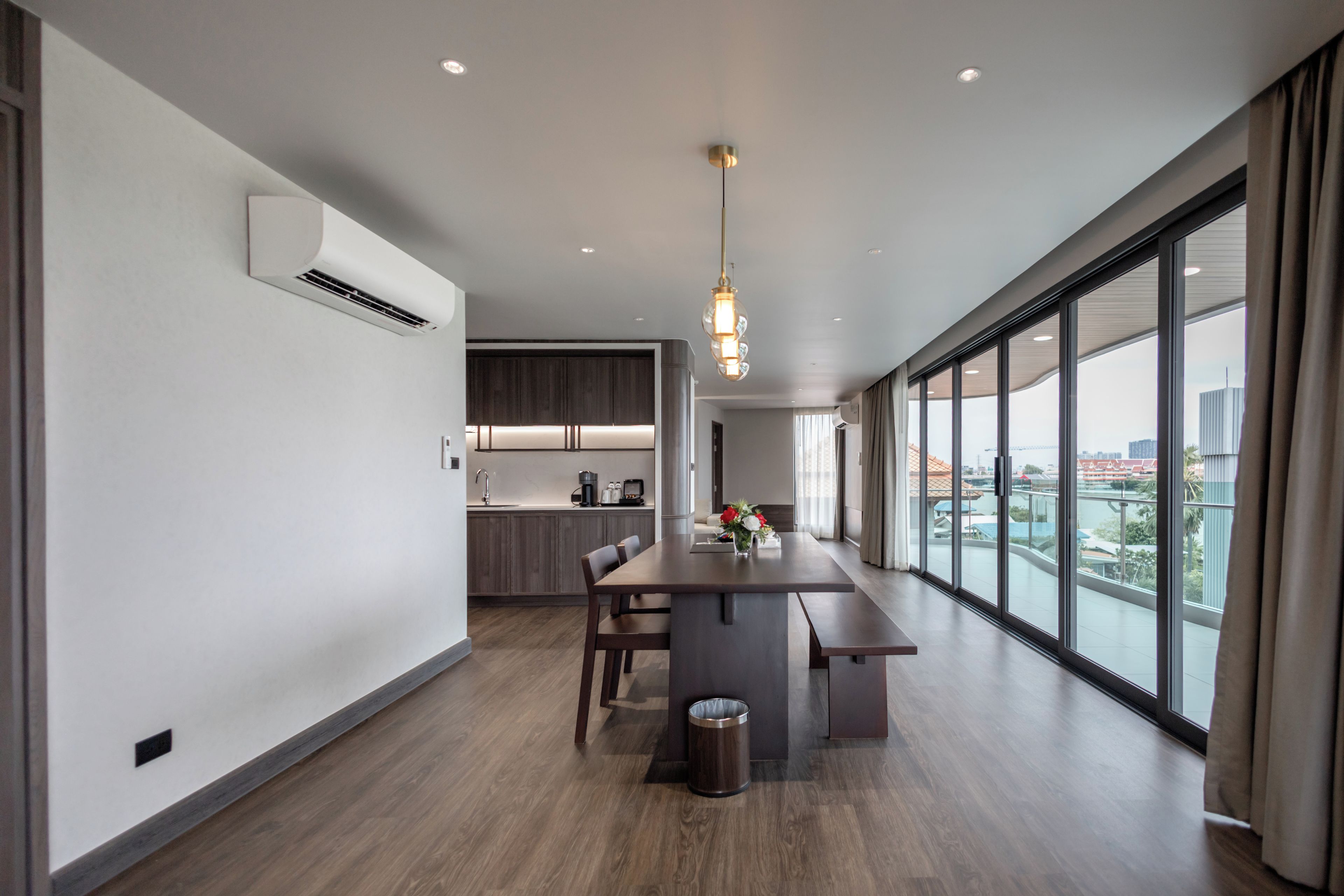 Una cocina moderna con armarios de madera oscura, una isla central con asientos y vistas de la ciudad a través de amplios ventanales.