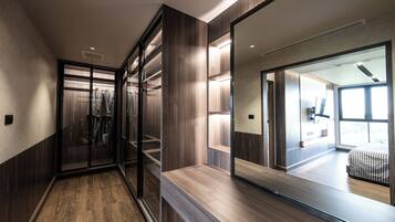 A modern hotel room with a large mirror, wooden flooring, and a view of the adjacent room.