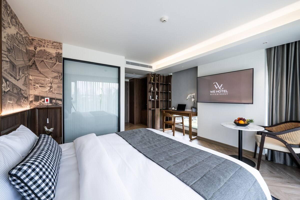 A modern hotel room with a bed, desk, and seating area.