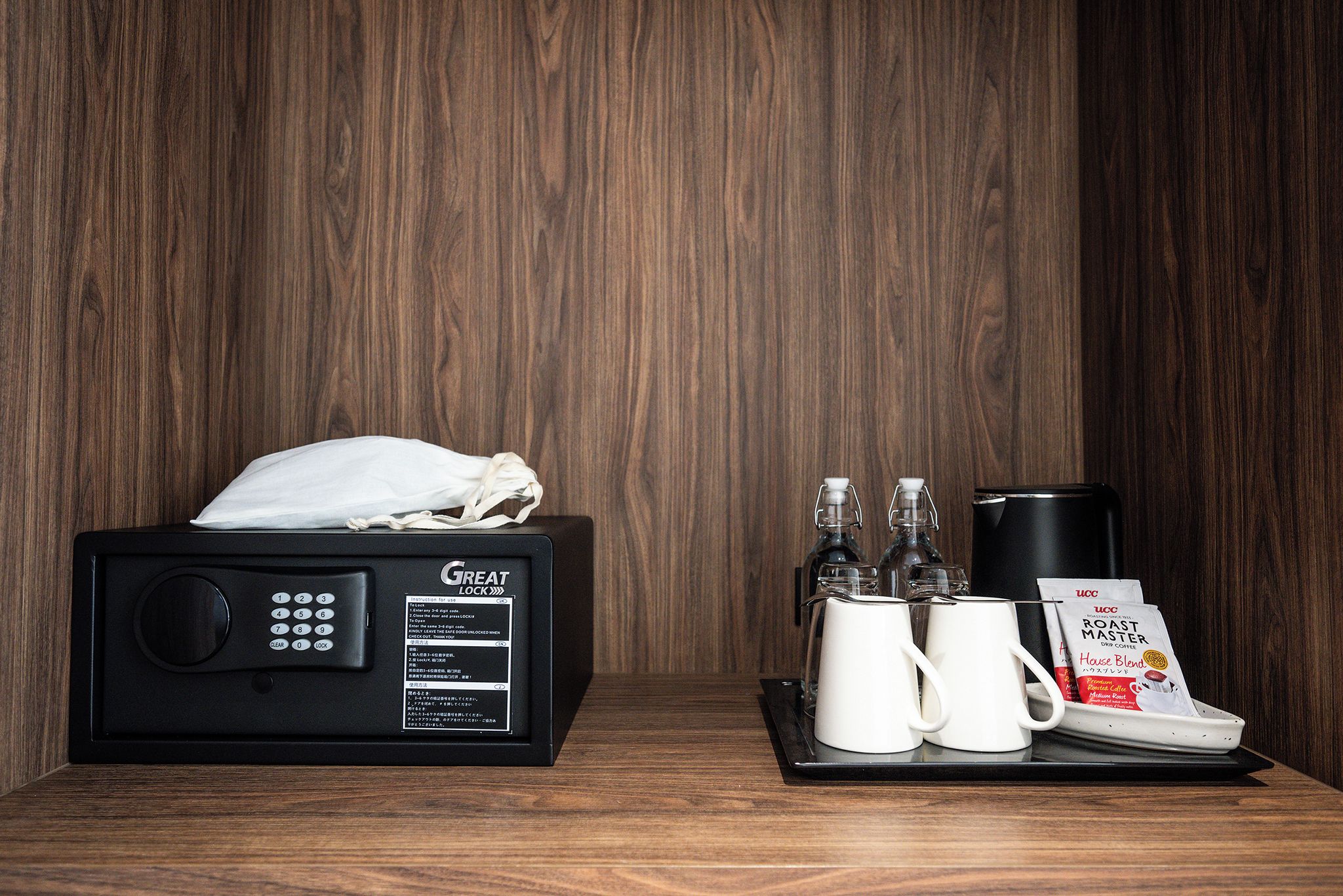 A microwave with a Great Lock, two white mugs, a coffee maker, a glass carafe, and a coffee pod on a tray.