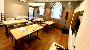 A conference room with tables, chairs, and a projector screen. - We Hotel Riverfront (Bangkok)
