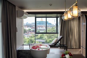 Een moderne badkamer met een badkuip, een raam met uitzicht op een stadsgezicht en een ligbed.