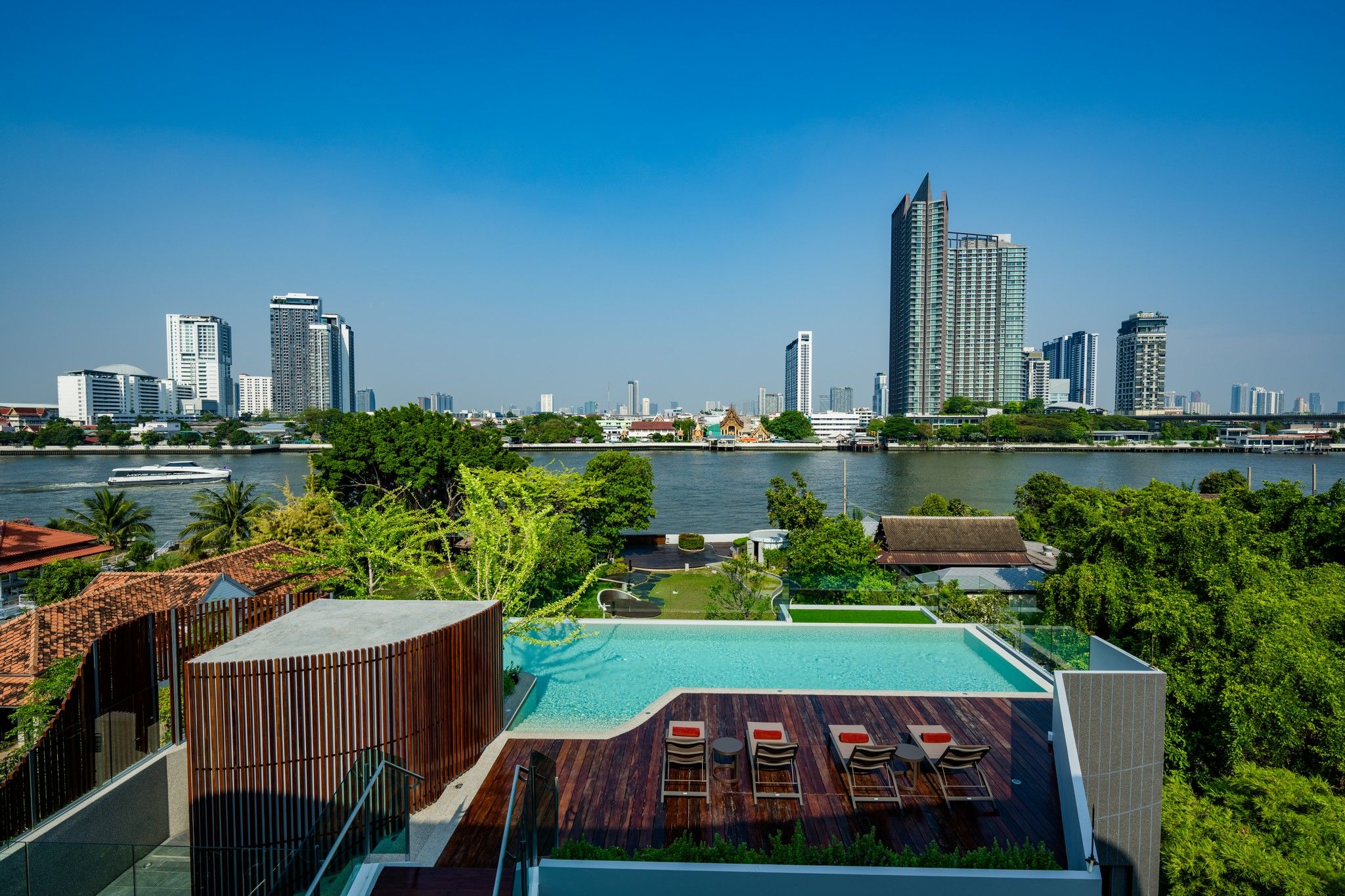A rooftop pool with a city skyline view, modern architecture, and a body of water.