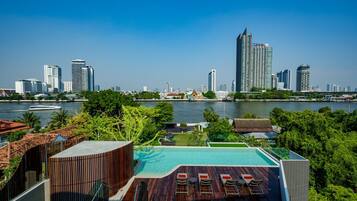 A rooftop pool with a city skyline view, modern architecture, and a body of water.