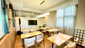A conference room with tables and chairs, a flat-screen TV, and a large window with curtains. - We Hotel Riverfront (Bangkok)