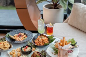 Une table avec divers plats et boissons, une plante en pot et un canapé à l’arrière-plan.
