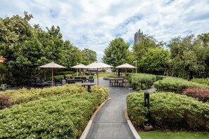 A landscaped outdoor area with seating arrangements and pathways. - We Hotel Riverfront (Bangkok)