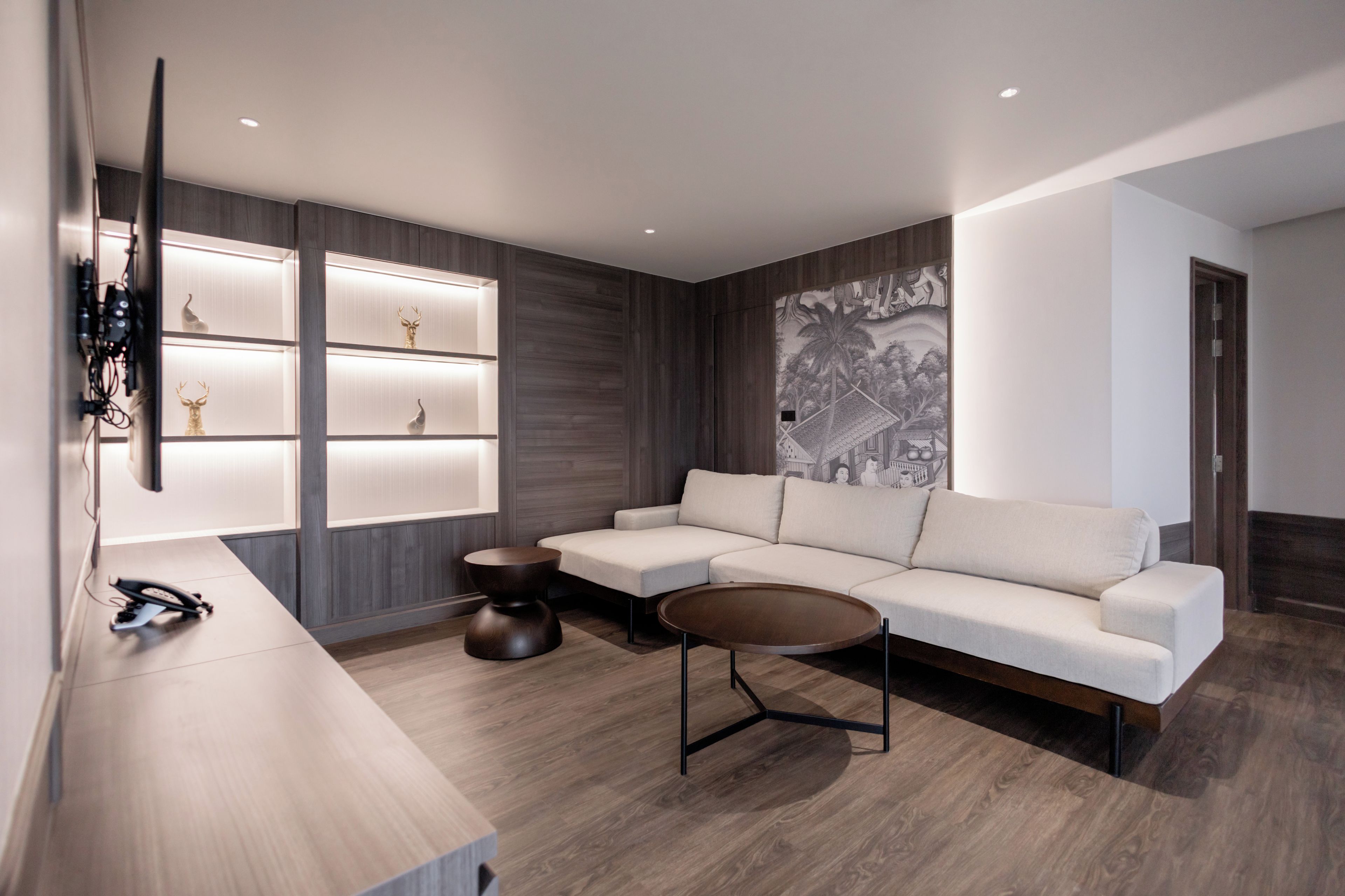 Una sala de estar moderna con un sofá seccional, una mesa de centro y un televisor montado en la pared.