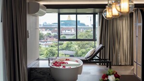 Une salle de bain moderne avec une baignoire, une fenêtre donnant sur un paysage urbain et un fauteuil de relaxation.