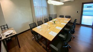 Ein Konferenzraum mit einem langen Tisch, Stühlen und einem kleinen Beistelltisch mit einer Flasche und Gläsern.