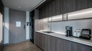 A modern kitchen with wooden cabinets, a stainless steel sink, and a coffee machine. - We Hotel Riverfront (Bangkok)