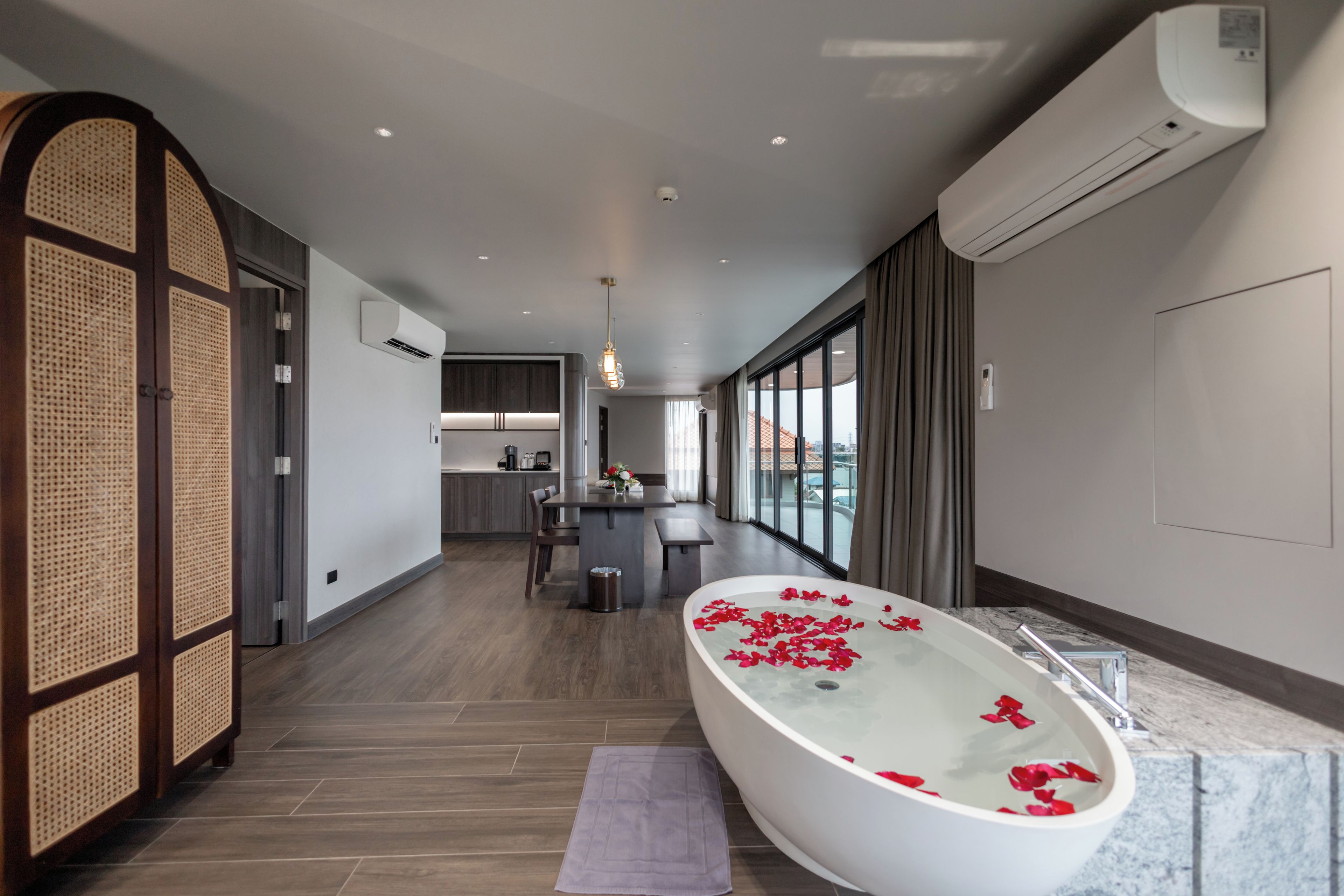 A modern bathroom with a freestanding bathtub, a wooden partition, and a view of the city.