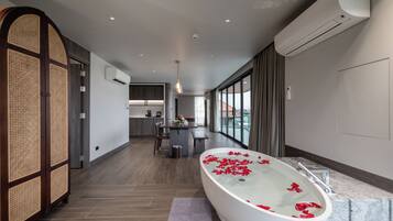 A modern bathroom with a freestanding bathtub, a wooden partition, and a view of the city.