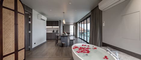 A modern bathroom with a freestanding bathtub, a wooden partition, and a view of the city.