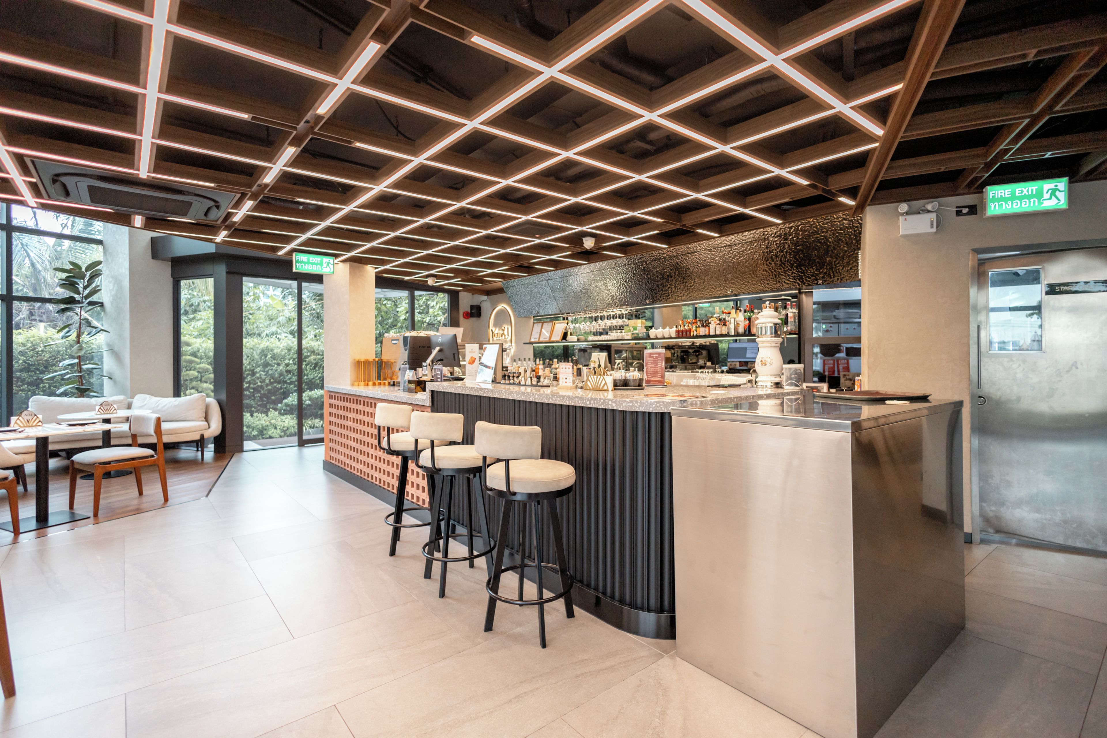 A modern bar area with a counter, stools, and a view of the outdoors.