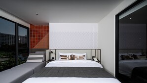 Ein modernes Hotelzimmer mit einem großen Bett, einer Couch und Blick auf die Stadt.