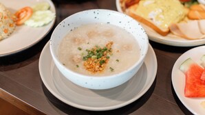 A dining table with various dishes including a bowl of soup, plates of food, and a bowl of soup garnished with green onions. - We Hotel Riverfront (Bangkok)