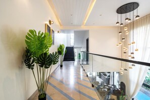 A modern interior with a glass railing, a staircase, and potted plants. - Staymaster Villa Novara - 3BHK  (Vagator)