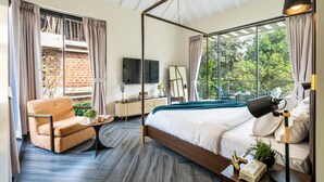 Een moderne slaapkamer met een hemelbed, een bank, een bijzettafeltje en een televisie.