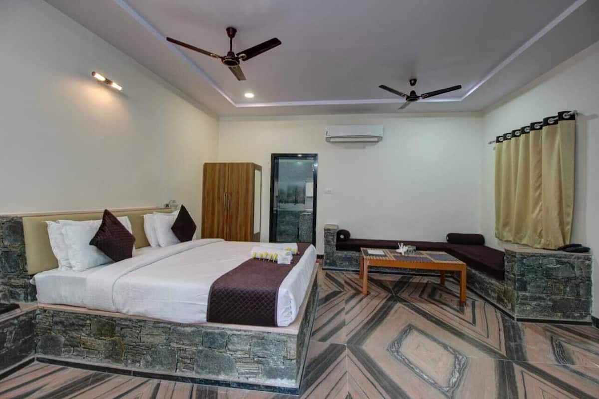 Una habitación de hotel con cama, sofá, una mesita y dos ventiladores de techo.
