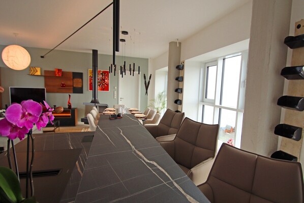 A modern interior with a long table, seating, and a fireplace.