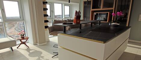 Una cocina moderna con una isla central, una zona de comedor con sofá y ventanas amplias con vistas.