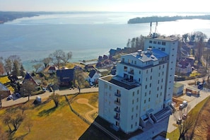 A high-rise building with multiple floors, a parking area, and a view of a lake.