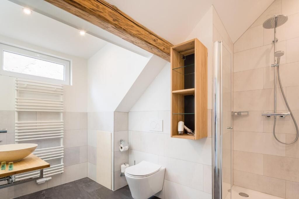 Ein modernes Badezimmer mit Dachfenster, einem Holzbadezimmer-Möbelstück, einer Toilette und einer Dusche.
