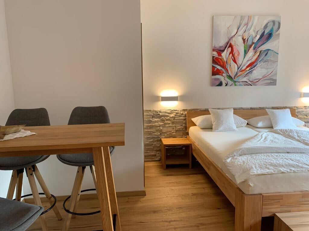 A bedroom with a bed, bedside table, and a painting on the wall.