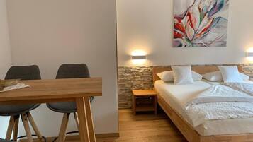 A bedroom with a bed, bedside table, and a painting on the wall.