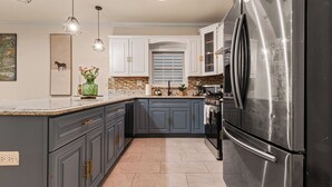 Cozinha moderna com bancadas de granito, eletrodomésticos de aço inoxidável e uma ilha grande.