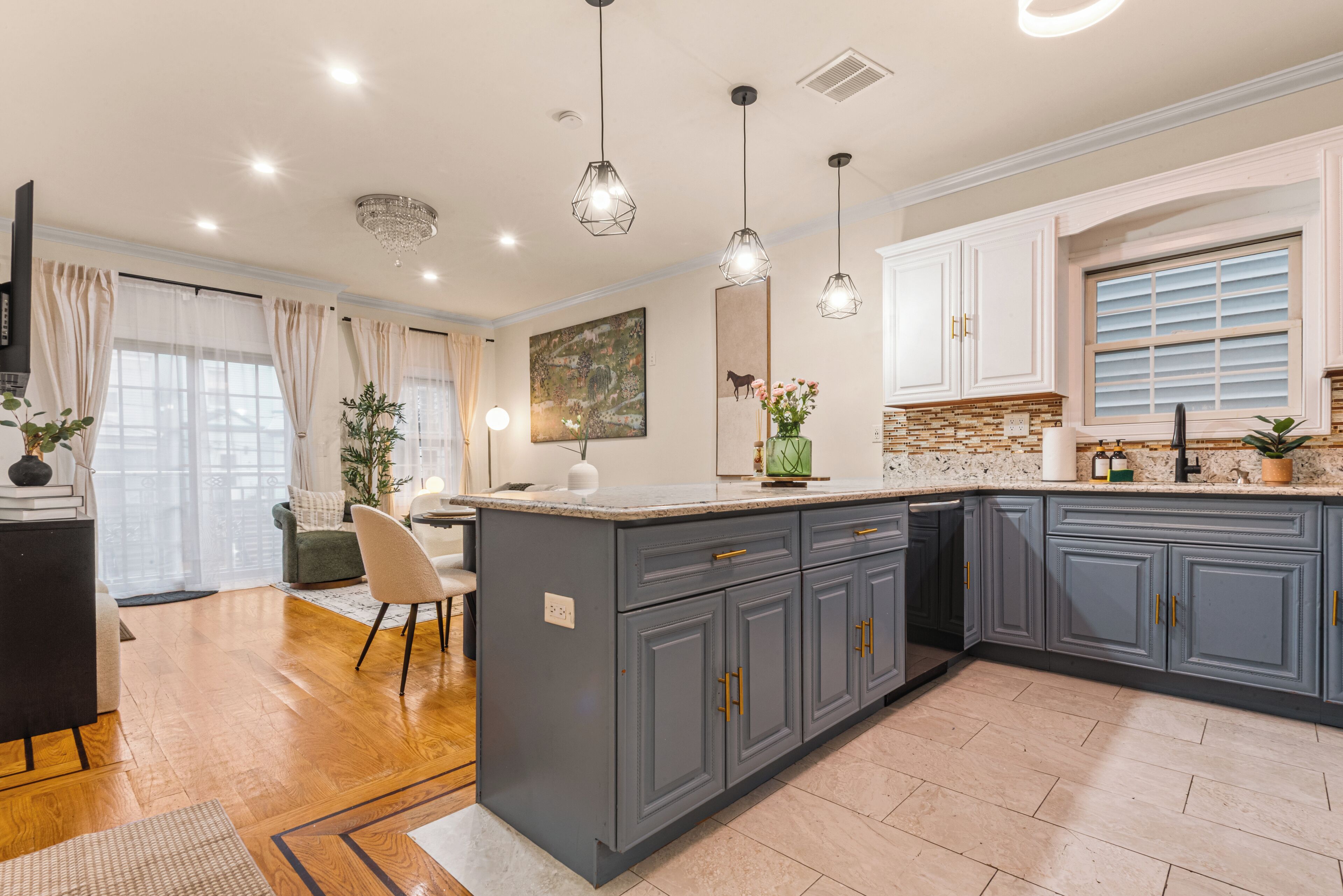A modern kitchen with grey cabinets, a granite countertop, and pendant lighting.
