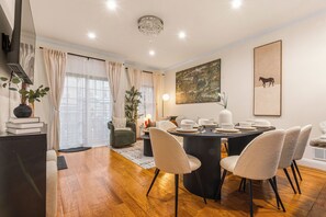 A dining area with a round table, four chairs, and a chandelier. - Prime Location! 5 Min Walk to PATH. NYC MetLife (Jersey City)