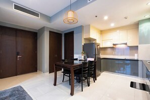 Eine moderne Küche mit dunklen Holzschränken, einem eingebauten Kühlschrank und einem Essbereich mit einem dunklen Holztisch und Stühlen.