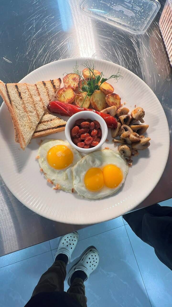 Un plato de comida con tostadas, huevos, frijoles, champiñones y papas asadas.