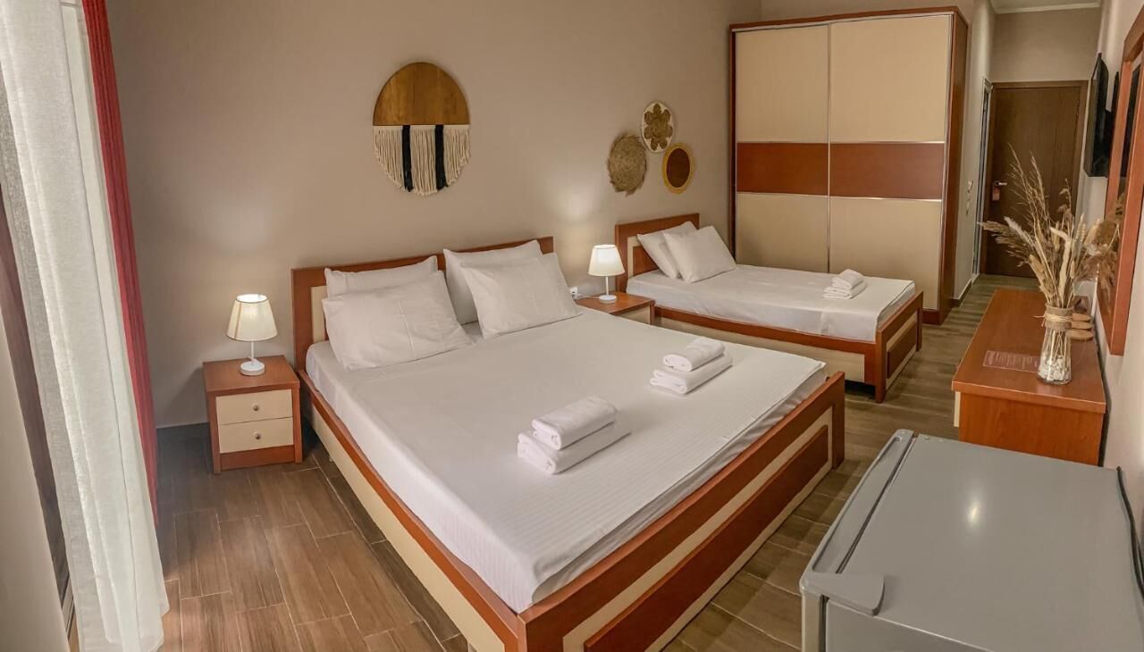 Een hotelkamer met twee bedden, een bureau, een stoel, een klein tafeltje en een garderobe.