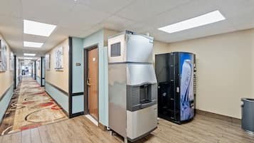 A hotel corridor with a water cooler, a refrigerator, and a vending machine.