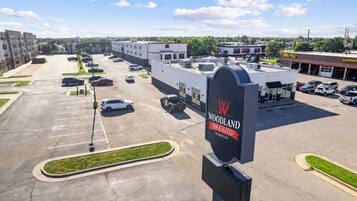 A parking lot with multiple cars, a Woodland Inn & Suites sign, and a Tire/PLLI Alignment building.