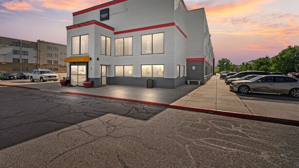 A multi-story building with a red and white color scheme, large windows, and a parking lot with cars.